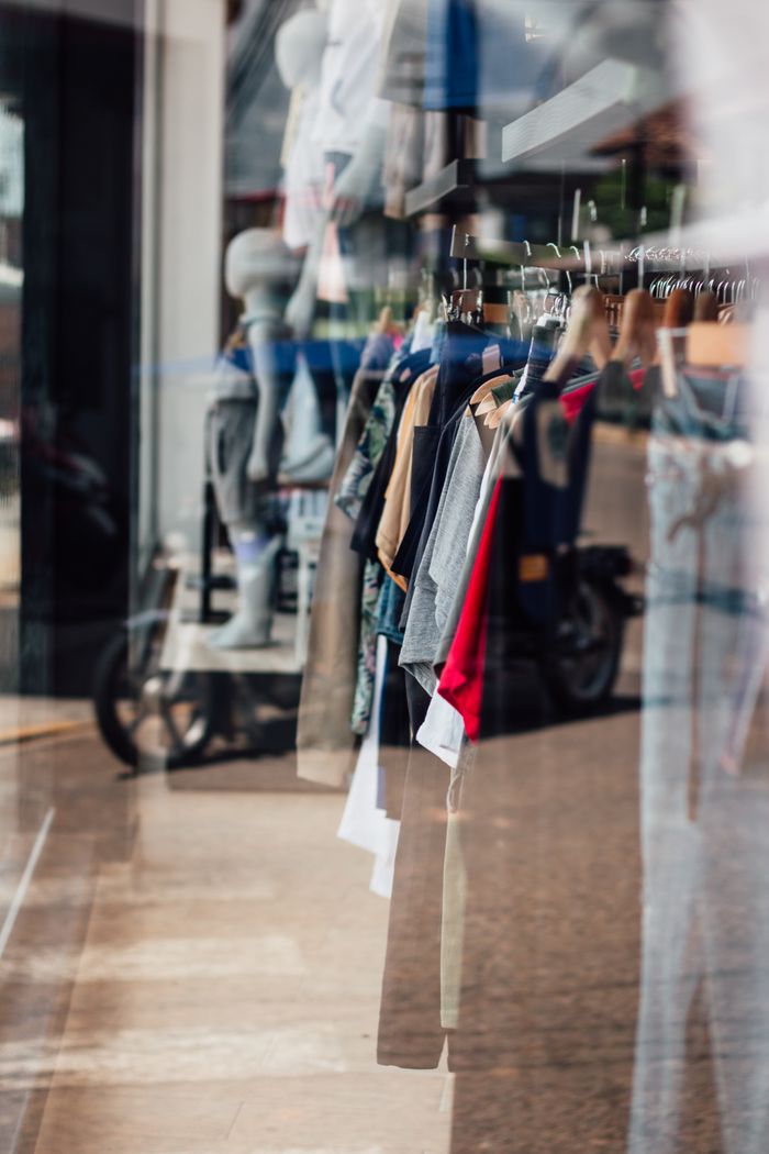 Vibrant clothing display in a Yurimaguas storefront window, showcasing various outfits and reflections.