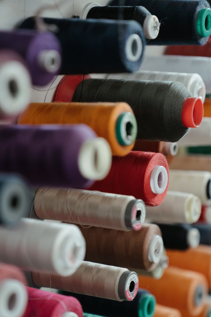A close-up view of colorful spools of sewing thread neatly organized on a rack.