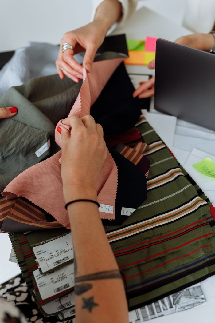 People sorting through fabric samples on a table, emphasizing textiles and collaboration.